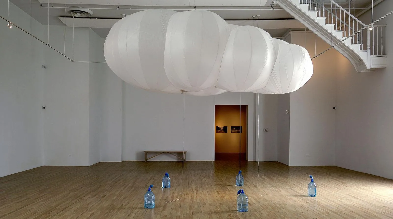 The Cloud: a large white cloud-shaped inflatable floating in a gallery above water bottles